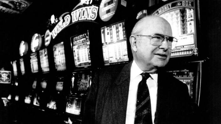 Len Ainsworth standing in front of a row of pokies machines