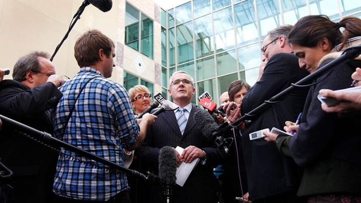 Andrew Wilkie surrounded by a crowd of reporters