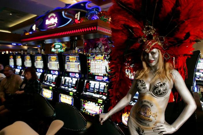 April Hanna, dressed as a showgirl, poses for photos by the new Las Vegas style slot machines at the Seminole Casino in Hollywood, Fla. Monday, Jan. 28, 2008 as the tribe began to use the machines in their casinos under an agreement reached with the State of Florida. (AP Photo/J. Pat Carter