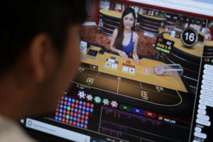 A screen shows Oriental Game, licensed to run an online gambling website in the Philippines, which has a live platform on its website for customers to interact with the young, female Chinese dealers. Photo: SCMP