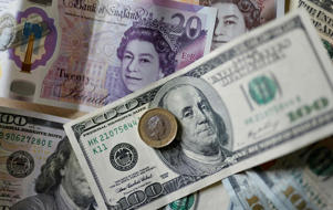 This file photo taken on 22 April 2022 shows pounds and US dollar banknotes displayed on a table in London (AFP via Getty Images)