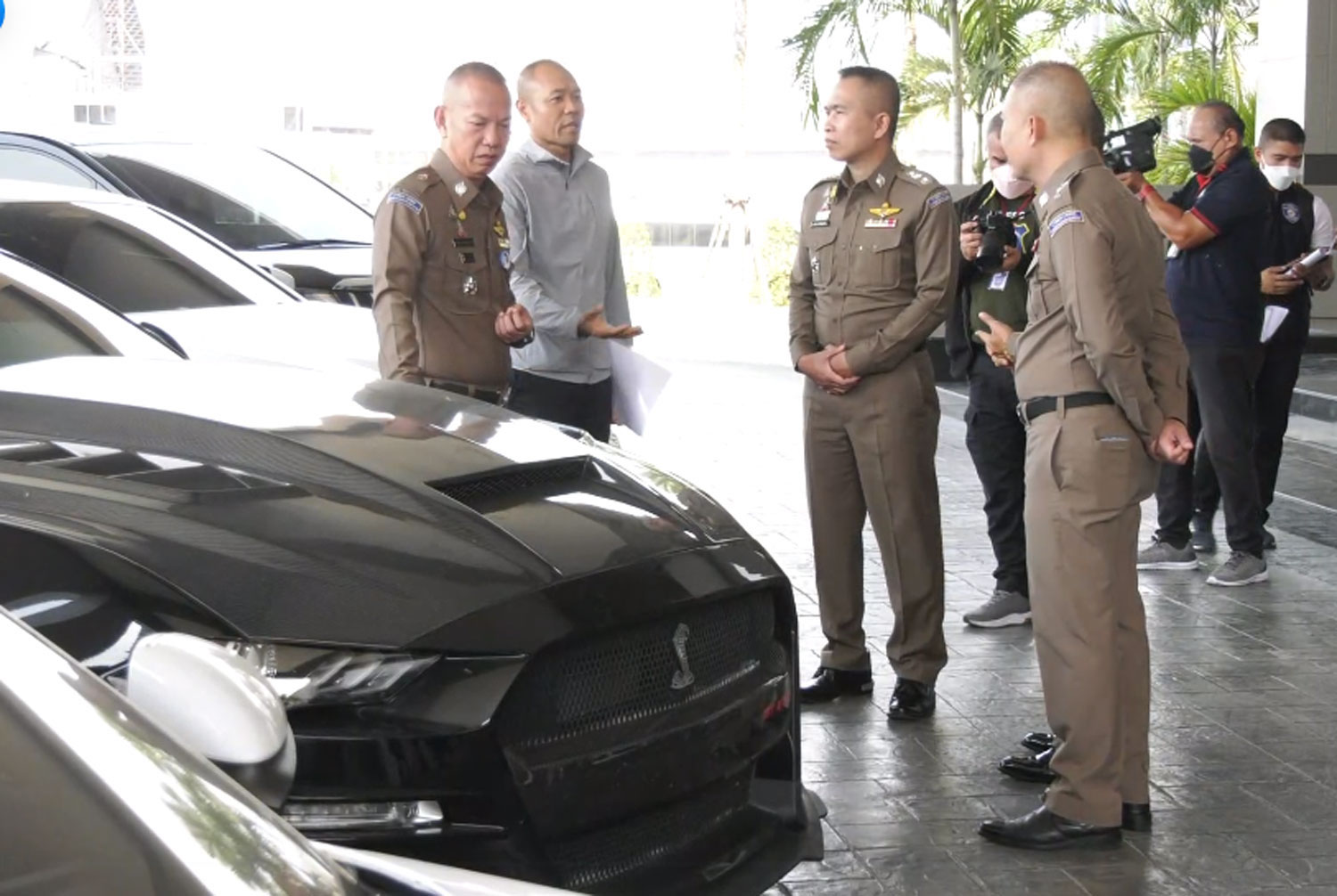 Pol Lt Gen Worawat Watnakhonbancha (left), head of the Cyber Crime Investigation Bureau, inspects five luxury cars seized from gambling suspects during a briefing on Saturday. (Captured from Police TV Facebook)