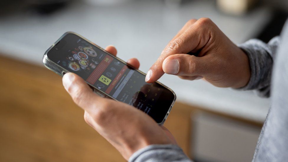 Close-up on a man betting online on a sports app on his mobile phone