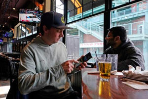 A Boston man looks at a mobile betting app, while watching a college basketball game at a sports bar near Fenway Park last month.