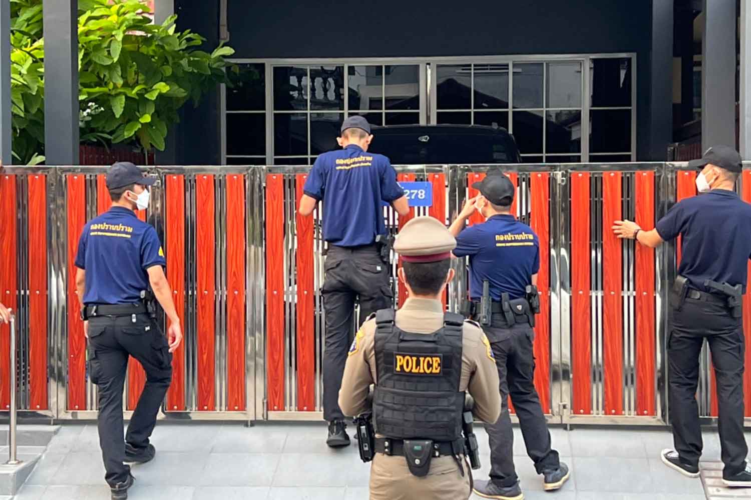 Police enter a house in Bang Na district, Bangkok, on Tuesday morning during raids against an online gambling network allegedly run by a police inspector. (Police photo)