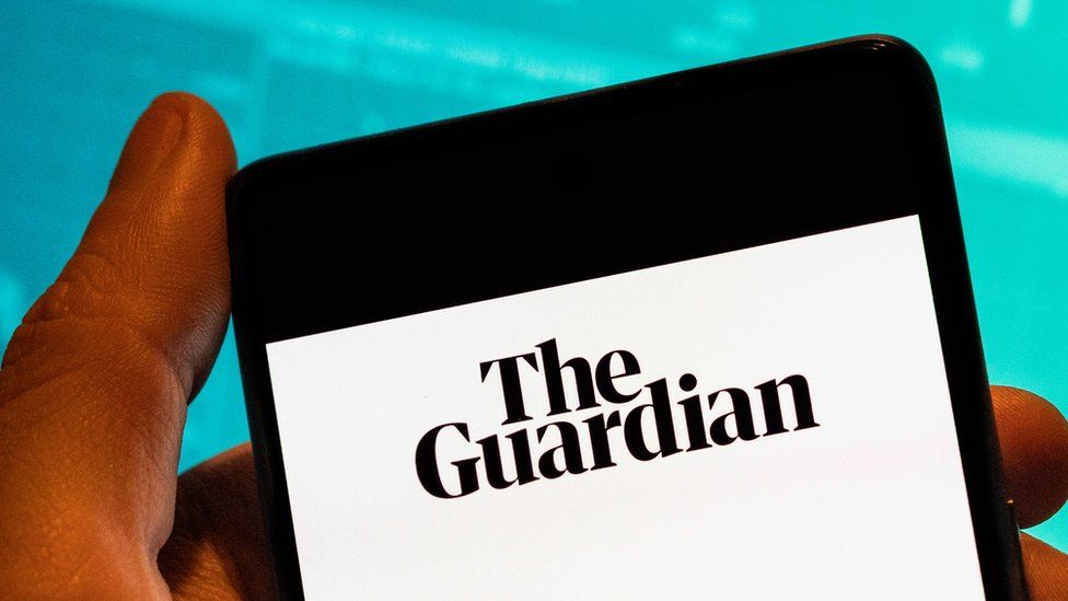 A person holding a phone with The Guardian newspaper app on display