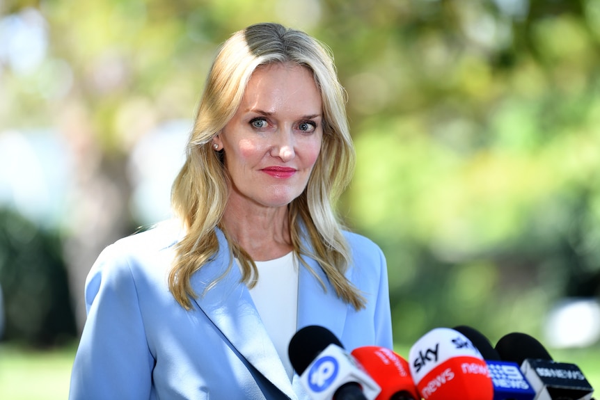 a woman standing behind microphones talking to the media