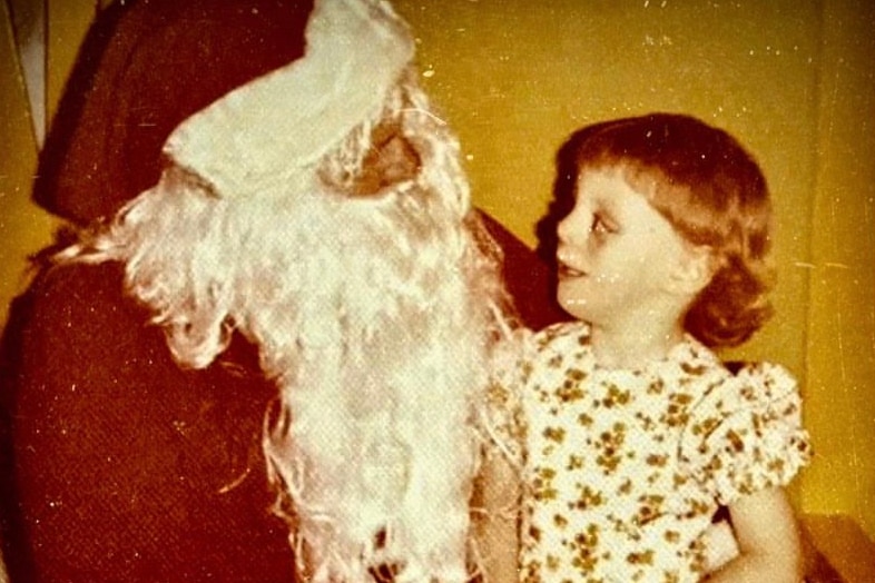 A young girl with a facial cleft sitting on Santa's knee. 