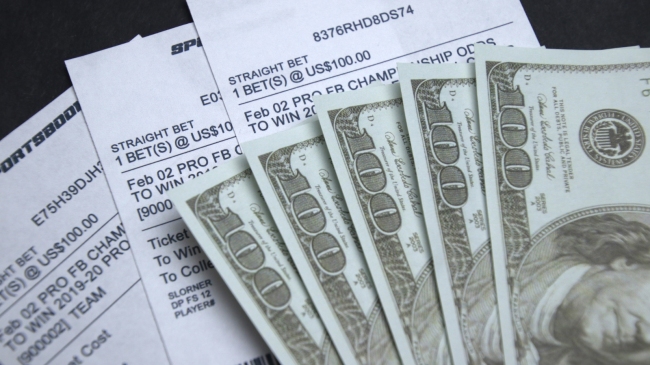 Cash sits atop a stack of sports betting tickets.