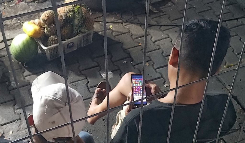 A man was seen accessing a slot gambling site on his mobile phone while in the South Jakarta area on Friday (24/11/2023).