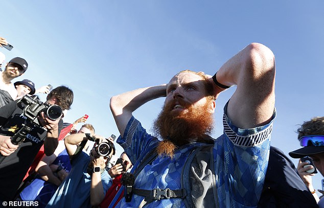 Cook appears emotional as he surrounded by photographers and supporters at the finish line