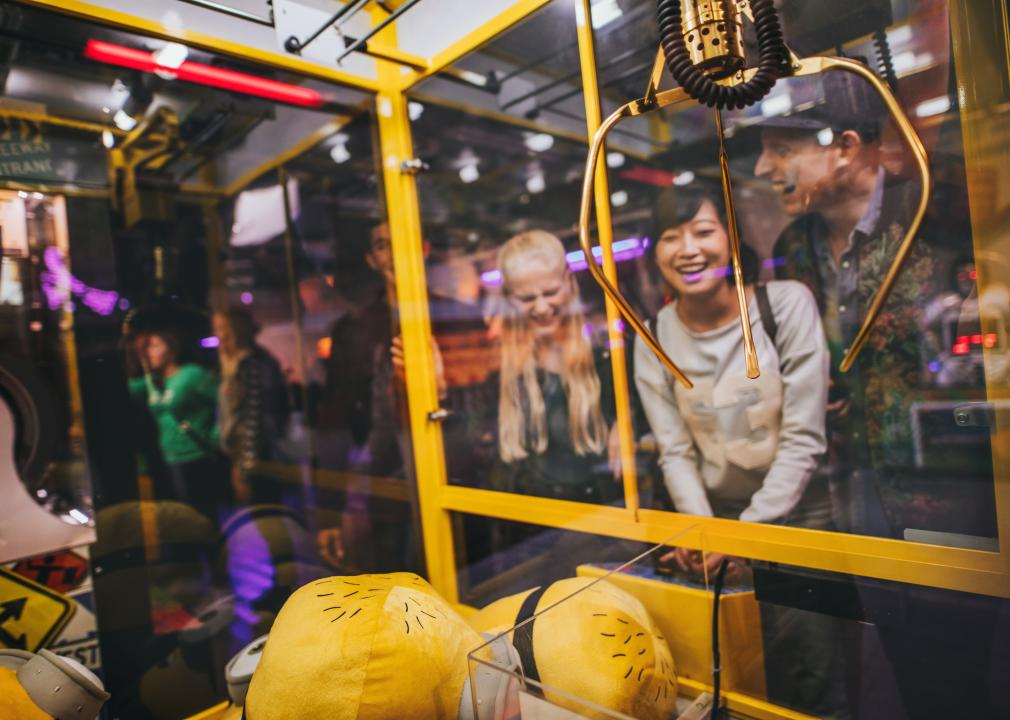 Group of friends playing with a claw machine.