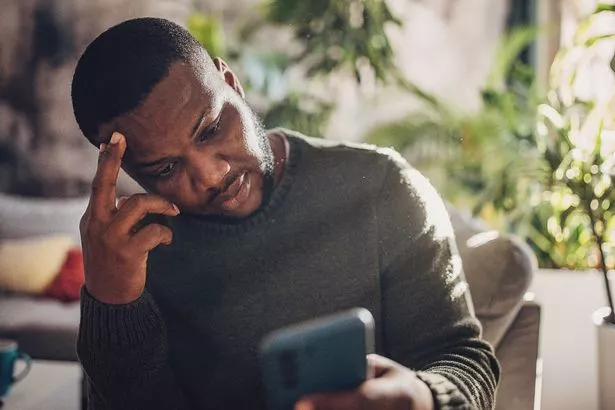 An adult man experiences defeat, following a live sports match on his smartphone, the disappointment evident as he faces a loss in his bet.