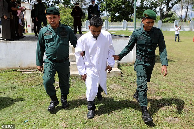 Sharia police lead a prisoner to receive his punishment after he was reportedly caught gambling - illegal under Sharia law