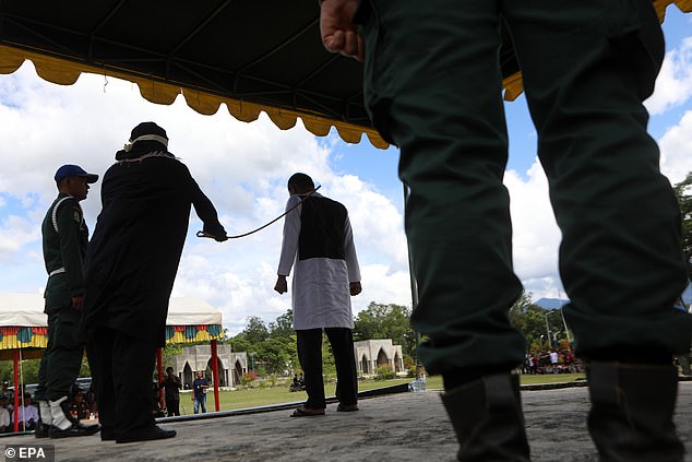 Officers watch on as a man, who is seen clenching his fists, is caned in Indonesia