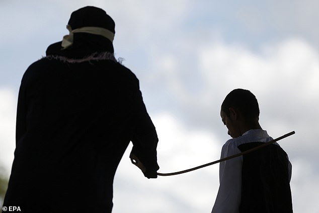 A cane makes contact with a prisoner's back as he is thrashed in the province of Aceh, Indonesia