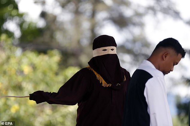 An executor known as 'algojo' conducts a public caning punishment in the city of Jantho, Aceh