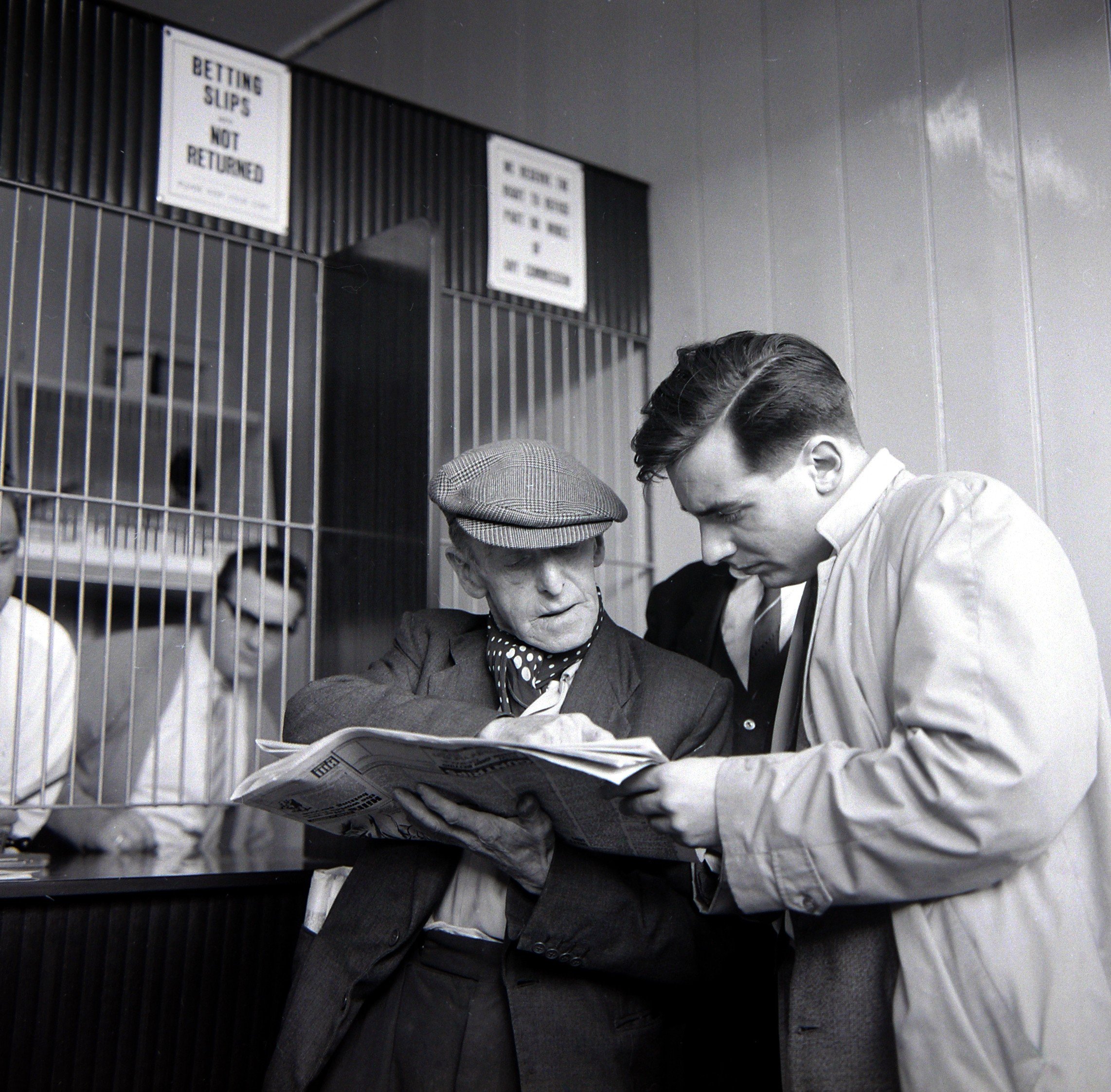 Punters studying the form guide before placing a bet at William Massey betting shop in Bethnal Green, London. 3rd May 1961. (Photo by George Greenwell/Daily Mirror/Mirrorpix via Getty Images)