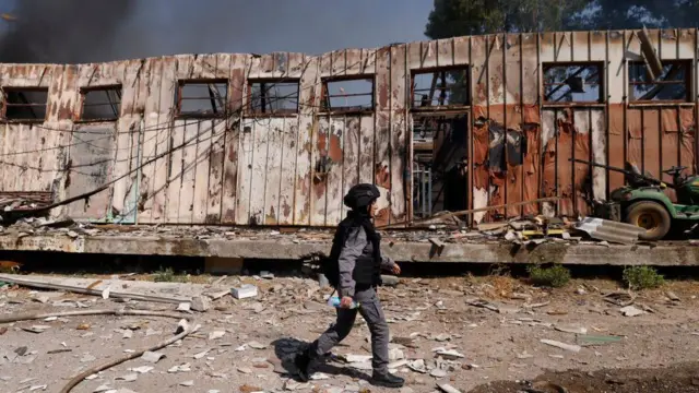 A member of Israeli security forces walks past a damaged building at the site of a rocket strike in Kiryat Shmona in northern Israel on 24 September