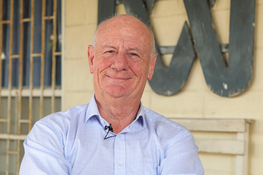 Tim Costello sits in front of a handpainted ABC lissajous logo