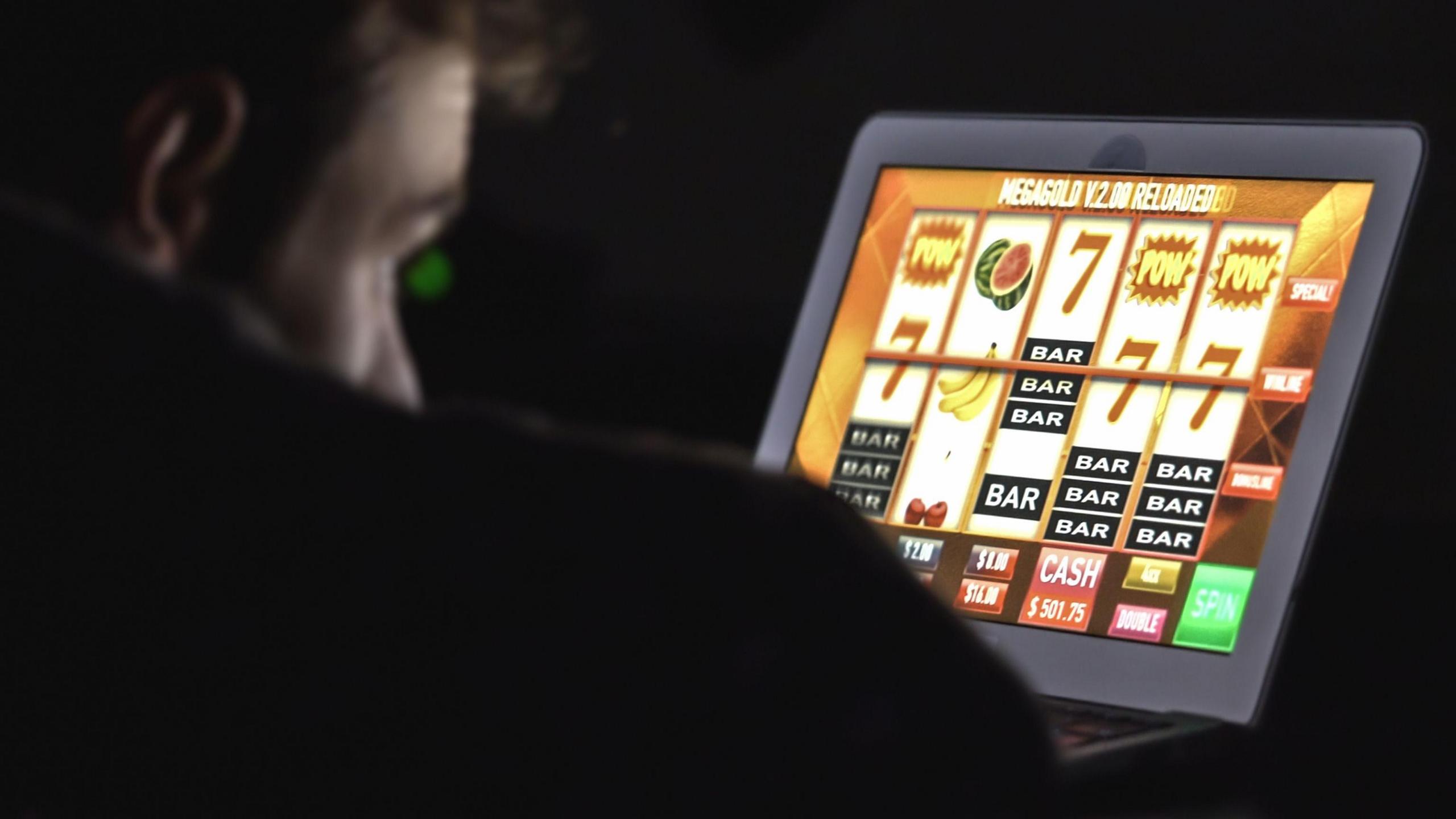 Man staring at an online casino slot machine on laptop computer at night