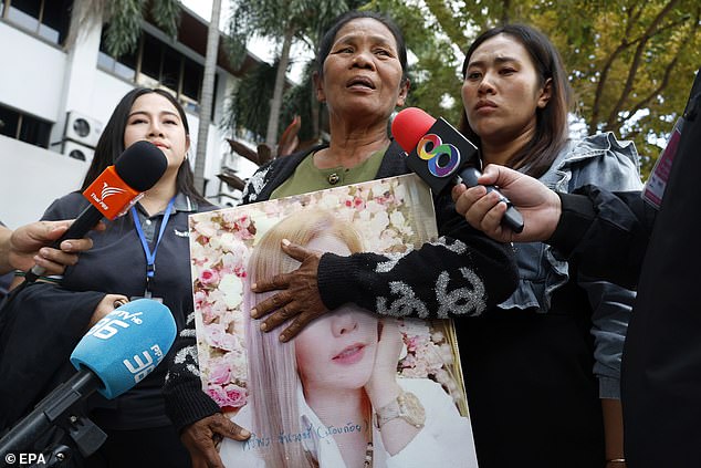 Thongpin Kiatchanasiri, mother of Siriporn 'Koy' Khanwong, holds a picture of her daughter while talking to the media outside the Criminal Court in Bangkok